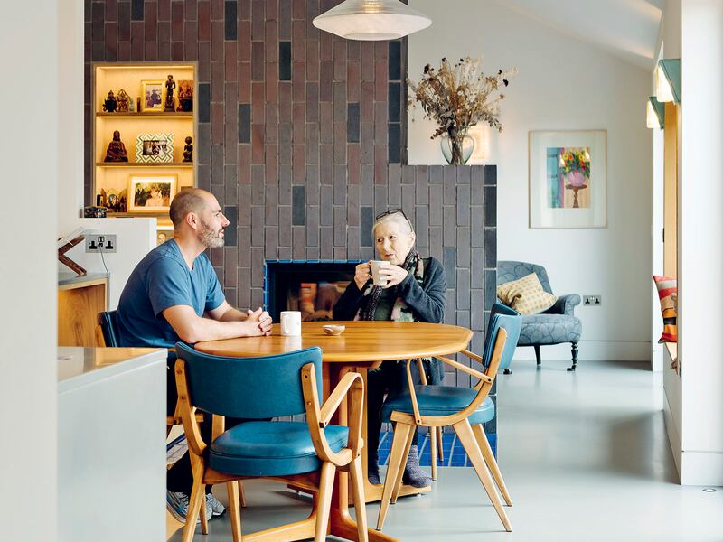 Mother and son sitting at kitchen table with coffee mugs