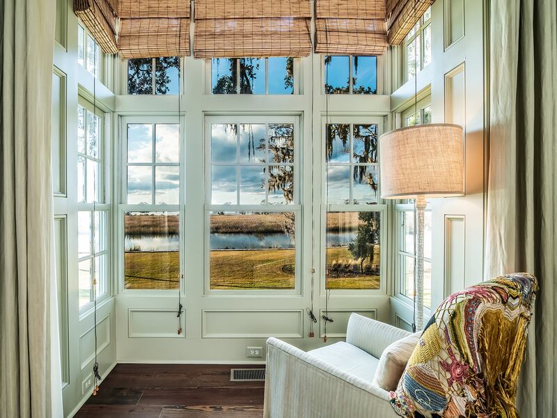 Large wooden window frame with a chair and lamp looking onto water
