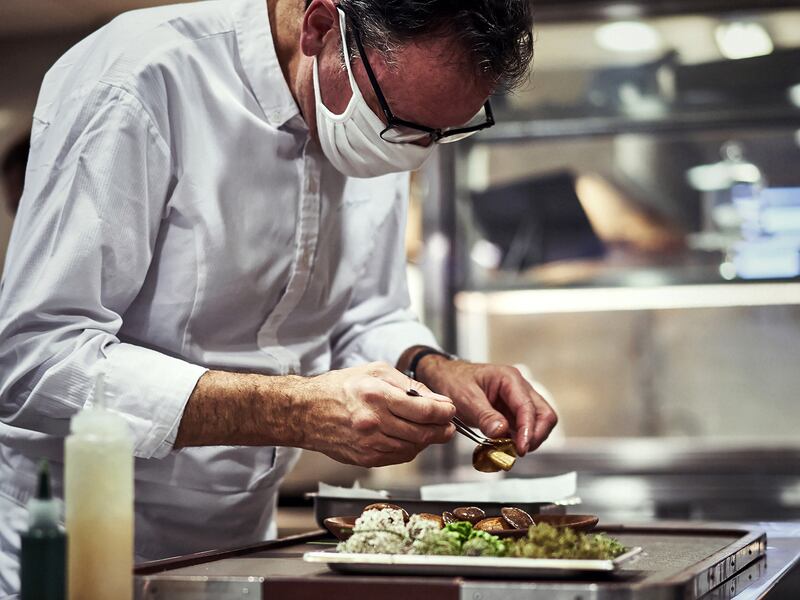 A chef assembles a fine dining dish using local mushrooms and herbs